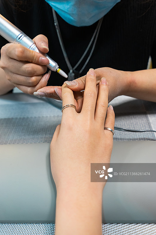 中国室内的美甲店，正在用锉刀和电子机器设备给顾客做美甲工作图片素材