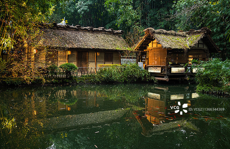 四川成都杜甫草堂景区中竹林掩映的茅草屋建筑和水中反射的倒影图片素材