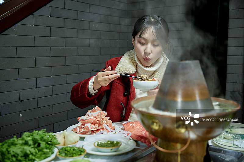 在饭店吃传统铜锅涮肉的亚洲少女图片素材
