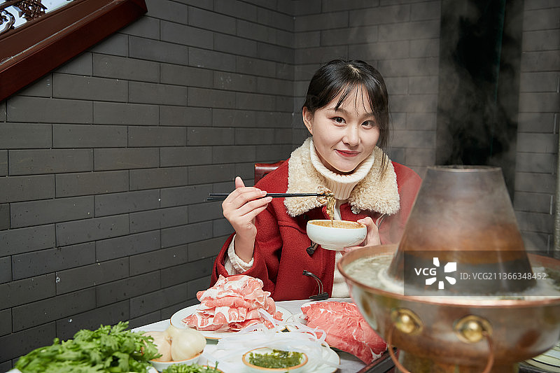 在饭店吃传统铜锅涮肉的亚洲少女图片素材
