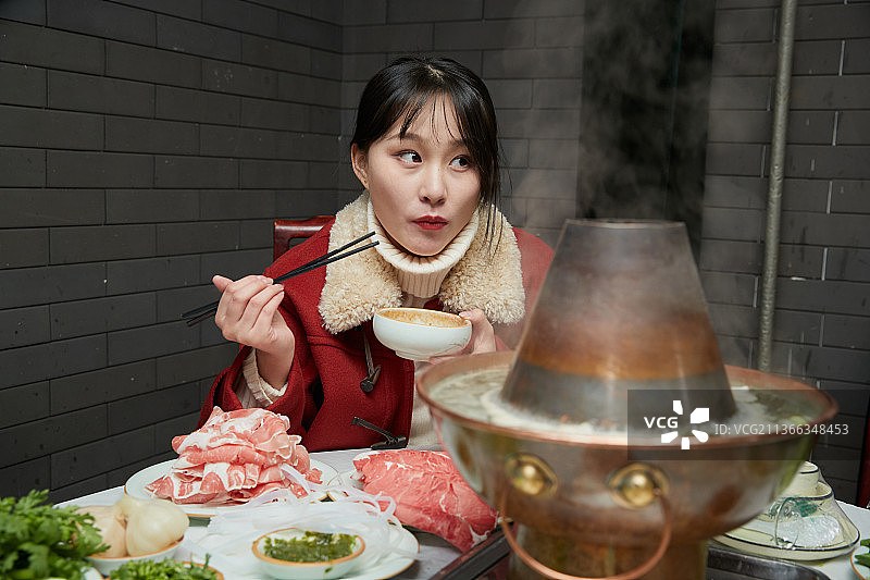 在饭店吃传统铜锅涮肉的亚洲少女图片素材