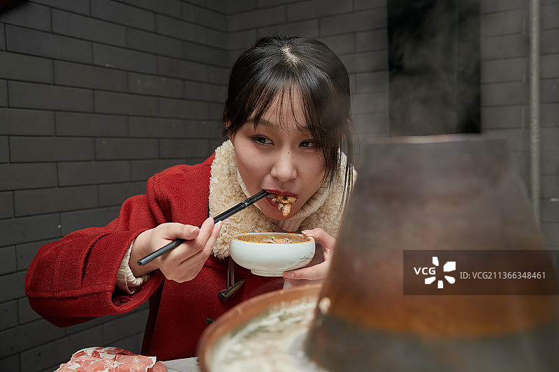 在饭店吃传统铜锅涮肉的亚洲少女图片素材