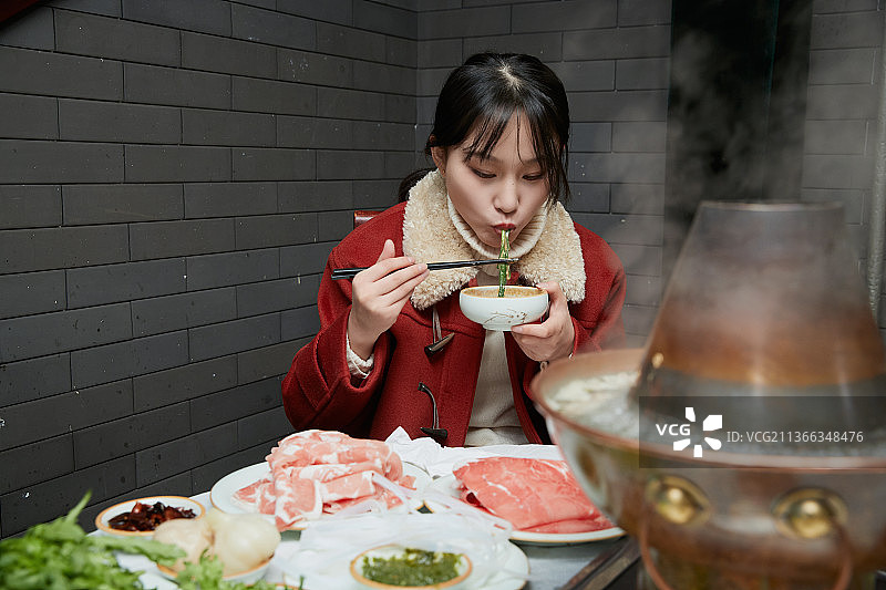 在饭店吃传统铜锅涮肉的亚洲少女图片素材