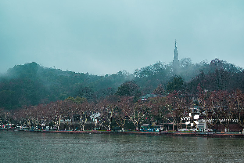 阴雨天在西湖泛舟，远眺云雾缭绕的宝石山，山上的石塔是保俶塔，刻了很多经文和浮雕图片素材