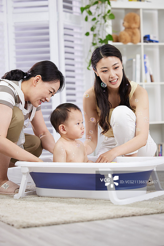 月嫂和年轻妈妈一起照顾宝宝洗澡图片素材