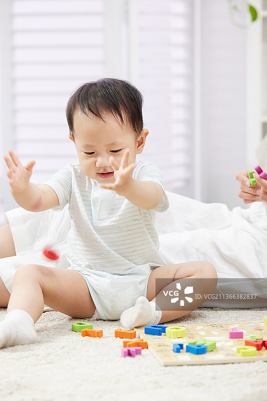 坐在地毯上玩玩具的快乐宝宝图片素材