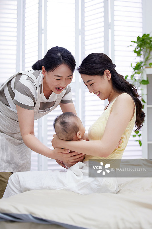 保姆和年轻妈妈一起照顾宝宝图片素材