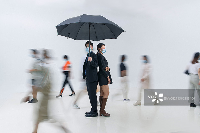拿着雨伞的商务男女戴着口罩站在人群中图片素材