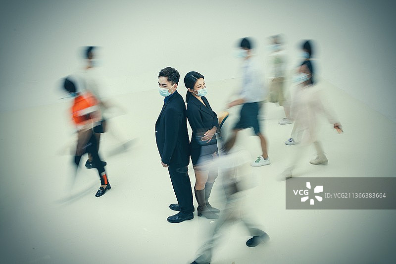 商务男女戴着口罩站在人群中图片素材