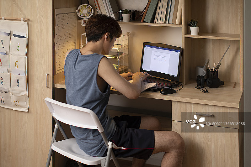 年轻大学生在宿舍使用笔记本电脑图片素材