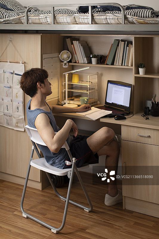 年轻大学生在宿舍使用笔记本电脑图片素材