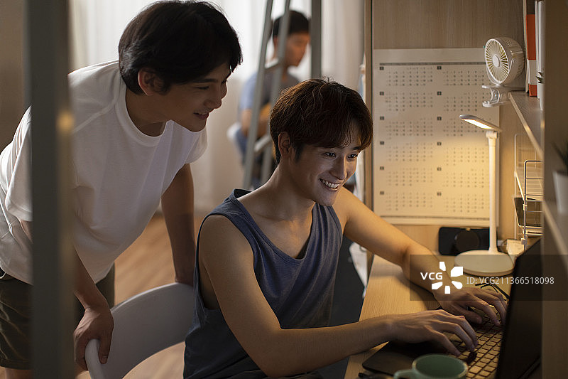 年轻大学生在宿舍使用笔记本电脑图片素材