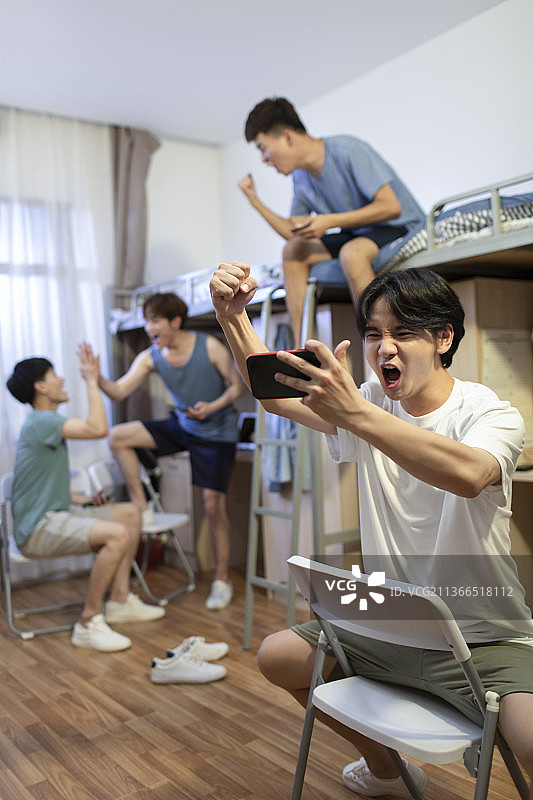 年轻大学生在宿舍玩手机游戏图片素材