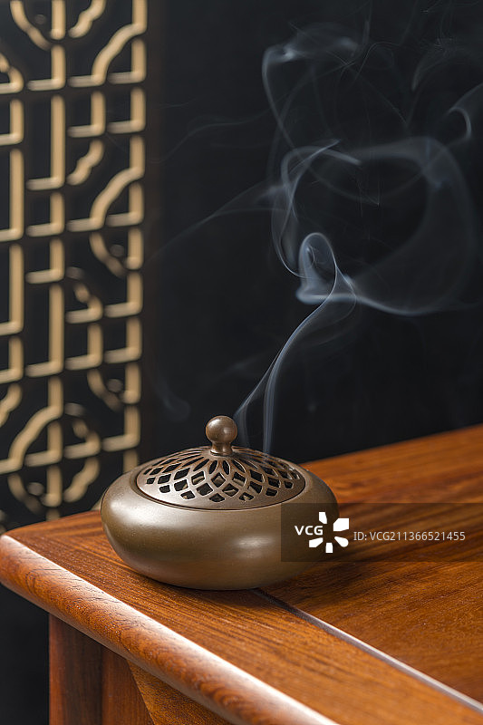 焚香的香炉佛珠线装书摆放在古窗棂木桌面上图片素材