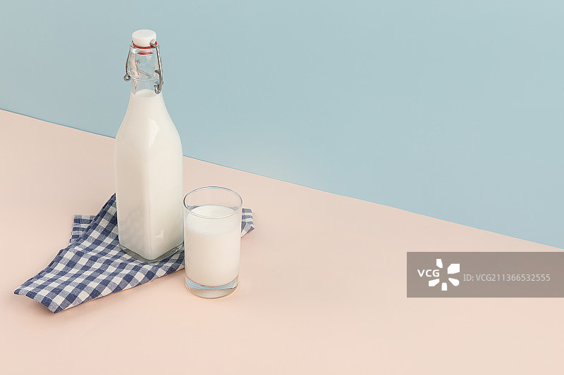 瓶装和玻璃杯中的牛奶，天蓝色背景图片素材