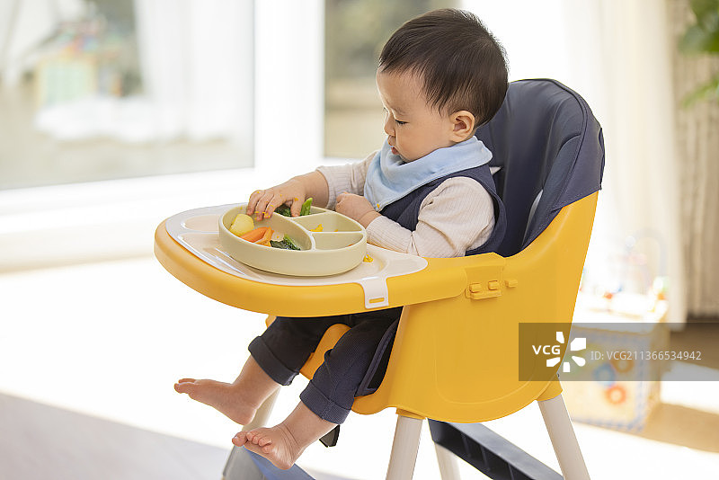 可爱的宝宝坐在儿童餐椅里图片素材