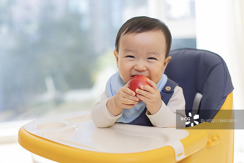 可爱的宝宝坐在儿童餐椅里图片素材