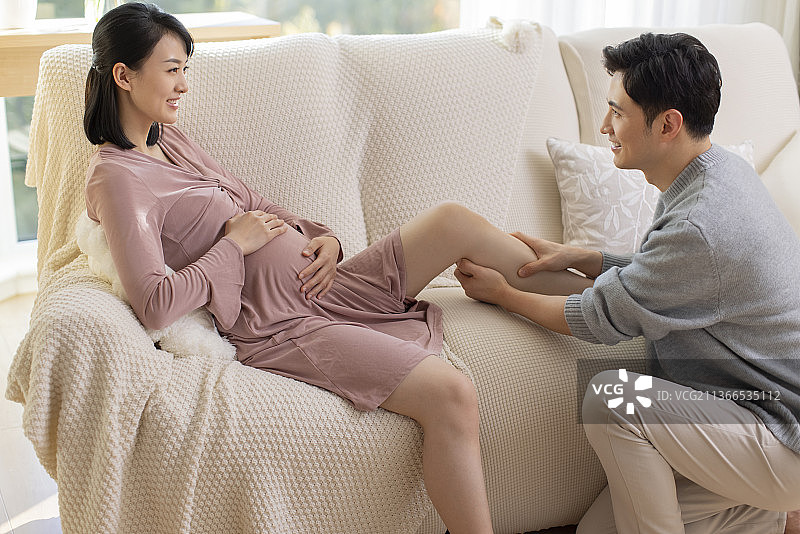 年轻丈夫在家照顾怀孕的妻子图片素材