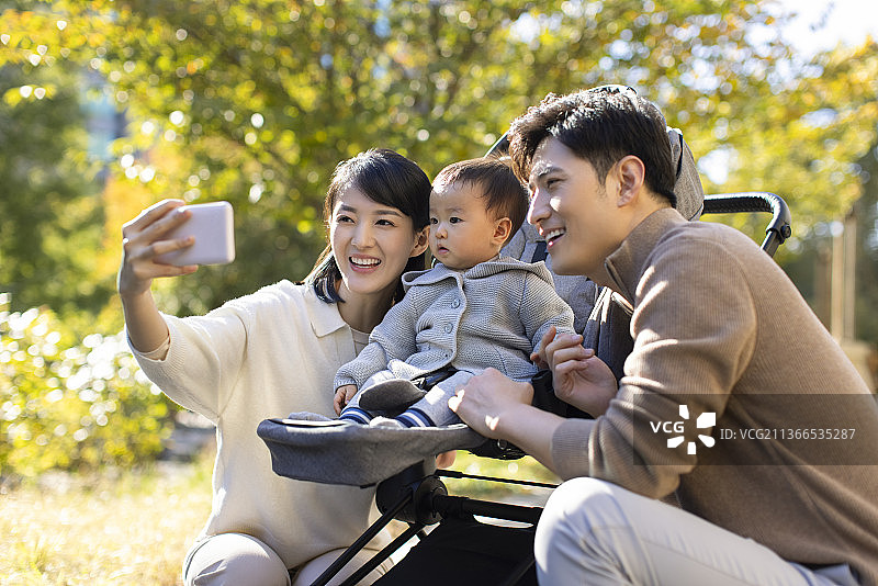 年轻父母在公园陪宝宝玩耍图片素材