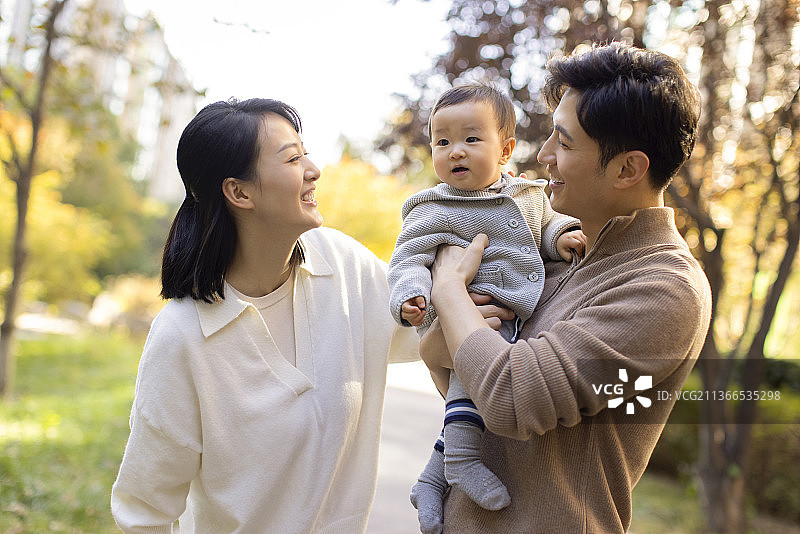 年轻父母在公园陪宝宝玩耍图片素材