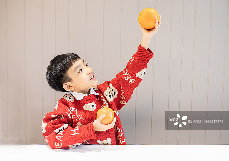 穿新年衣服玩橙子的小男孩图片素材