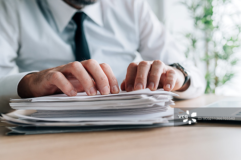办公桌前阅读报纸的商人，文书工作量图片素材