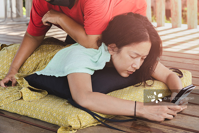 女人在泰国享受泰式按摩，同时使用手机图片素材