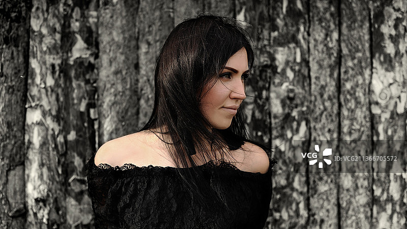 在俄罗斯鄂木斯克靠着树干眺望远方的年轻女子图片素材