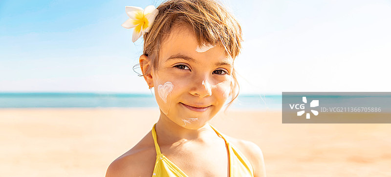 小女孩在脸上涂抹防晒霜图片素材