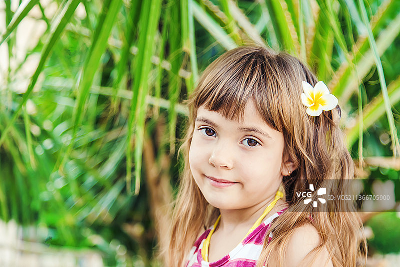 头戴鸡蛋花，背景是棕榈树的女孩图片素材