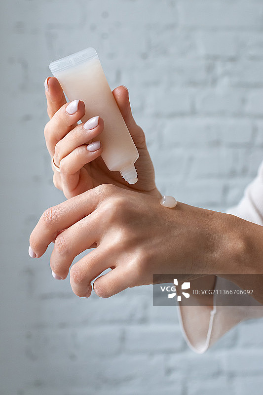 年轻女孩在光线下给手涂抹乳霜图片素材