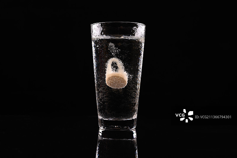 黑色背景中维生素C泡腾片在比玻璃杯中融化图片素材