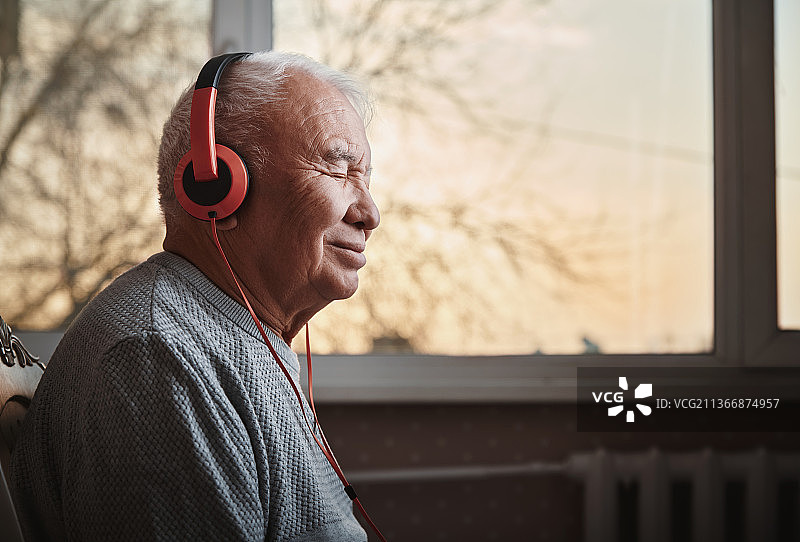 戴着耳机在家听音乐的年长男人图片素材