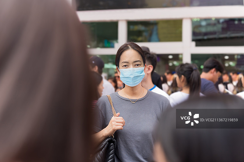 疫情风险：佩戴防护口罩的亚洲女性站在泰国人群中图片素材