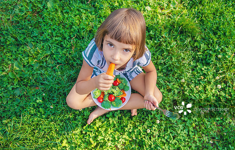 吃蔬菜西兰花和胡萝卜的小孩（选择性焦点）图片素材