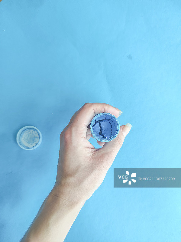 蓝色背景下，裁剪的手拿着避孕套图片素材