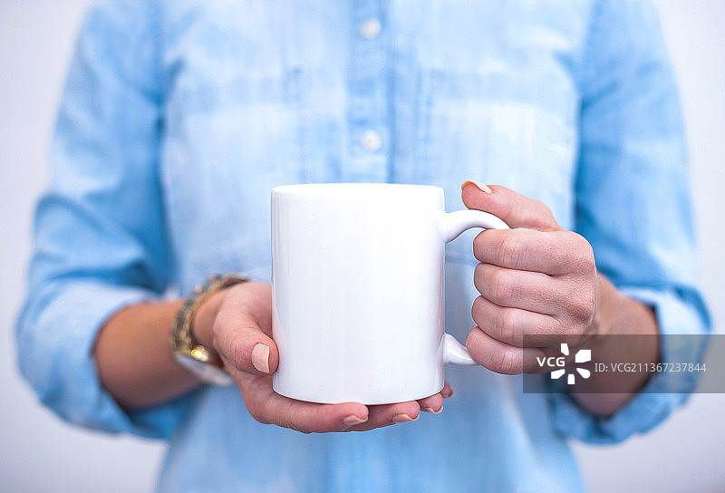 美丽女人的双手捧着一个大咖啡杯图片素材