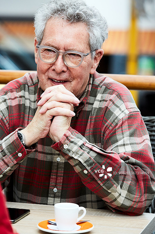 坐在咖啡馆喝浓缩咖啡与人交谈的年长男人肖像图片素材