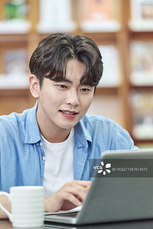在大学图书馆学习的微笑男大学生图片素材
