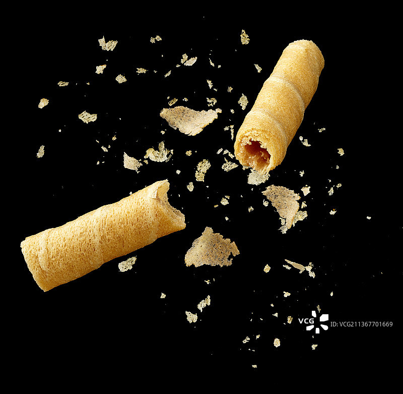 黑色背景前的折断碎开的蛋卷图片素材