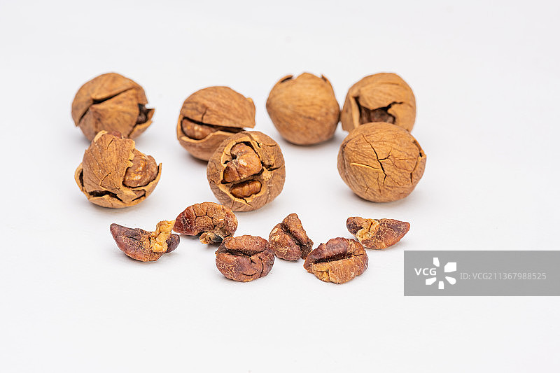 倾斜视角拍摄白色背景上的椒盐盐焗手剥临安山核桃图片素材