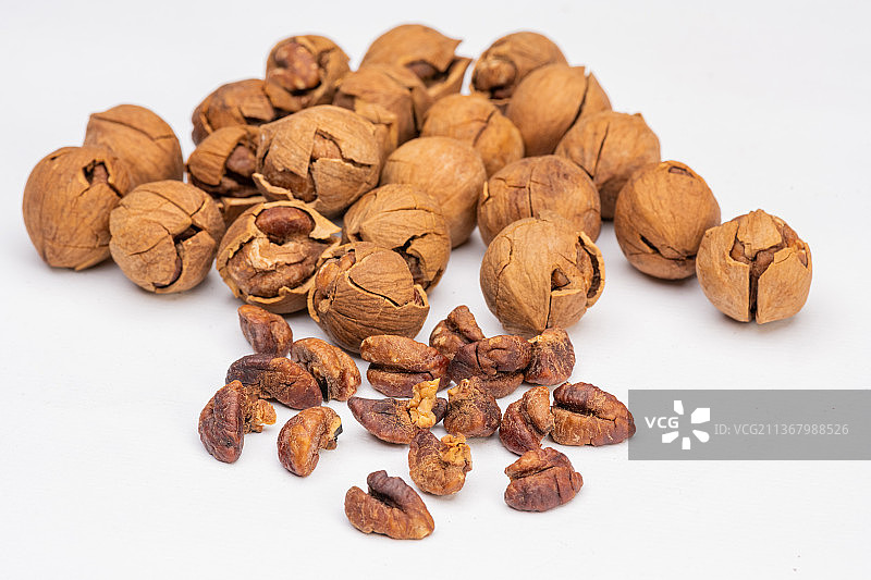 倾斜视角拍摄白色背景上的椒盐盐焗手剥临安山核桃图片素材