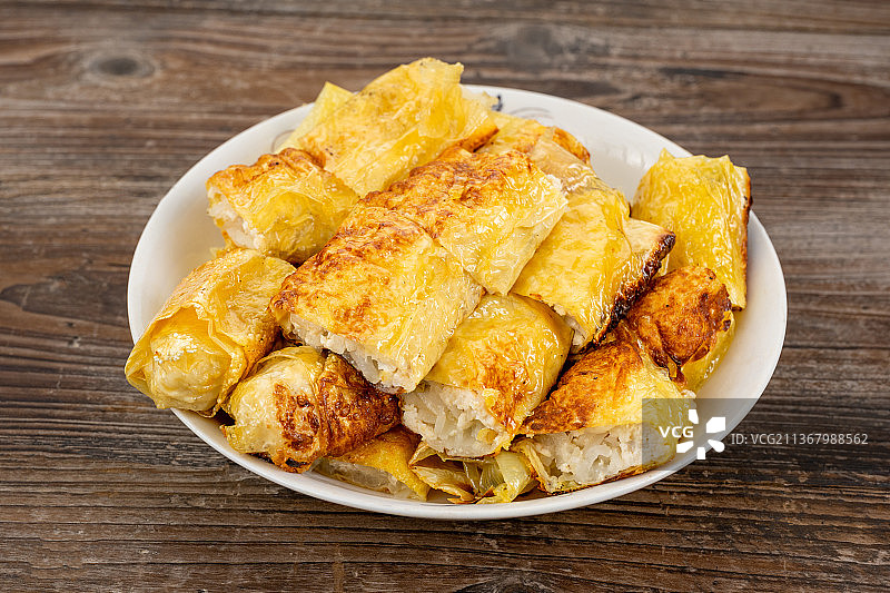 倾斜视角拍摄老桌木板上的豆皮卷图片素材