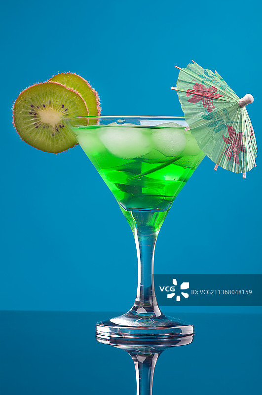 热带绿色冷饮：蓝色背景下的玻璃杯饮品特写图片素材