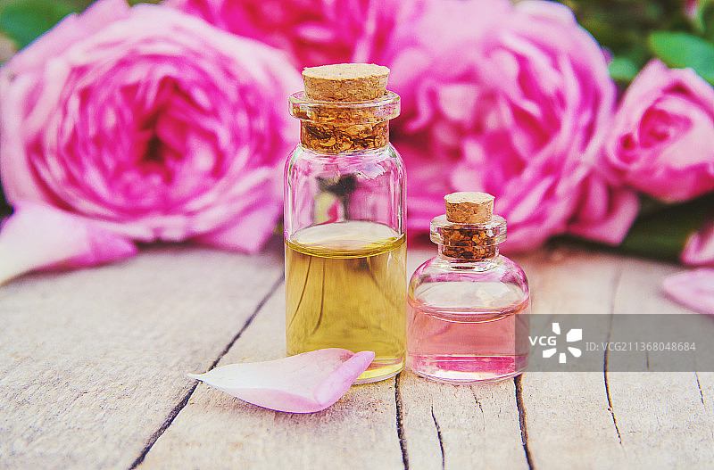 浅色背景上的玫瑰精油，选择性聚焦图片素材