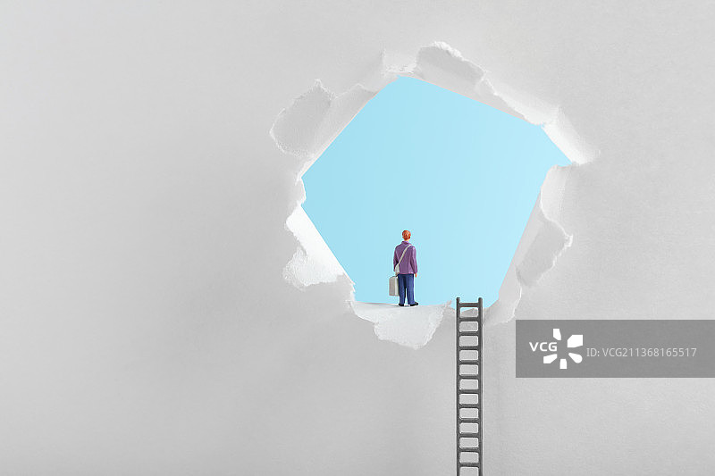 微缩创意爬上梯子站在纸洞出口的人图片素材