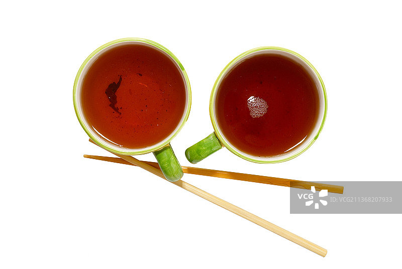 两只装有茶和筷子的茶杯，白色背景图片素材