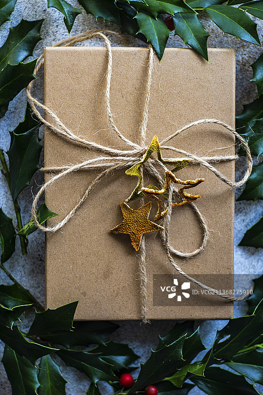 装饰有新鲜冬青浆果植物的乡村礼品盒在水泥背景上图片素材