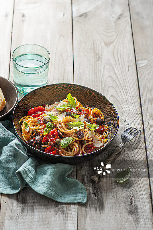 配番茄干酱、卡拉玛塔黑橄榄、大蒜、罗勒和帕尔马干酪的意面图片素材