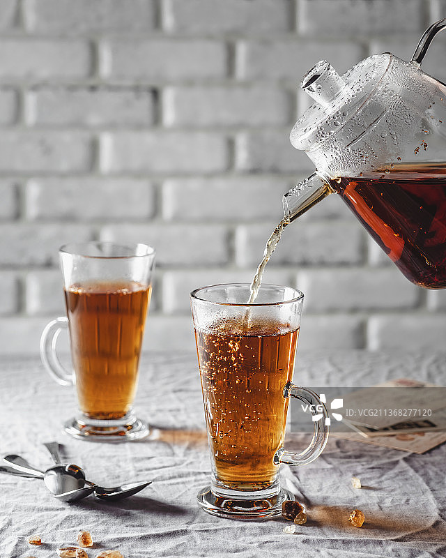 将博士茶从玻璃壶倒入茶杯中图片素材